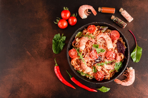 Tasty pasta with shrimp and tomato on a frying pan