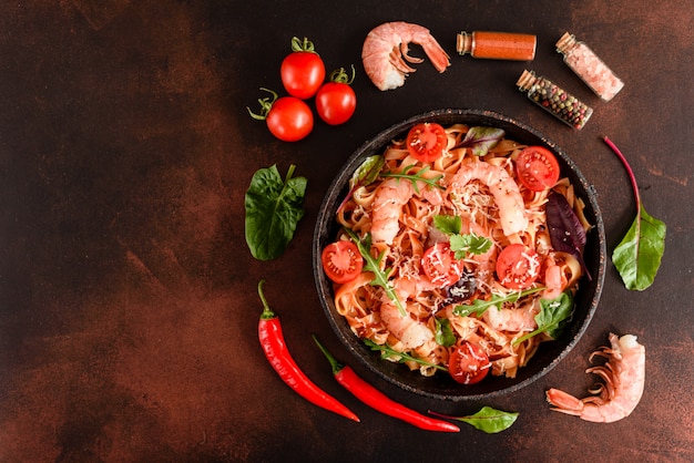 Tasty pasta with shrimp and tomato on a frying pan