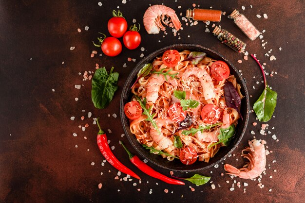 Tasty pasta with shrimp and tomato on a frying pan