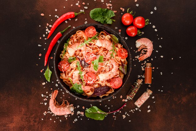 Tasty pasta with shrimp and tomato on a frying pan