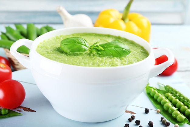 Tasty peas soup and vegetables on table close up