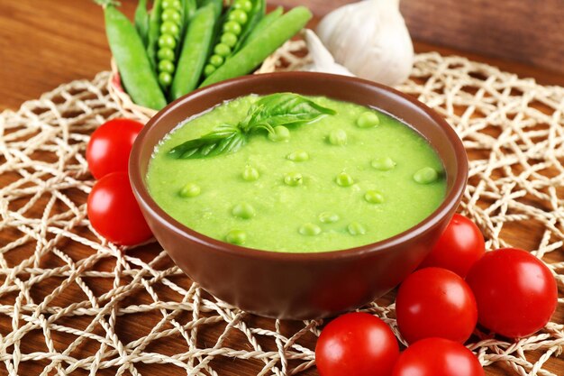 Tasty peas soup and vegetables on table close up