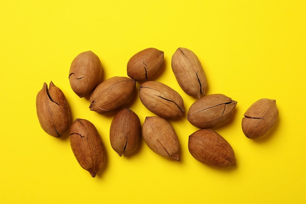 Tasty pecan nuts on yellow, top view