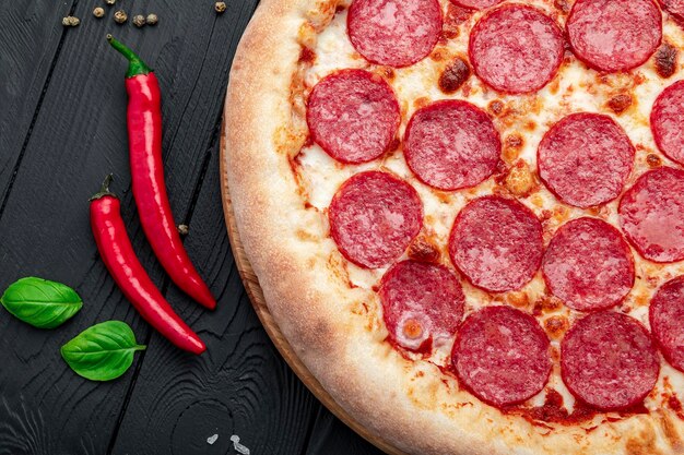 Foto gustosa pizza ai peperoni e ingredienti per cucinare pomodori basilico