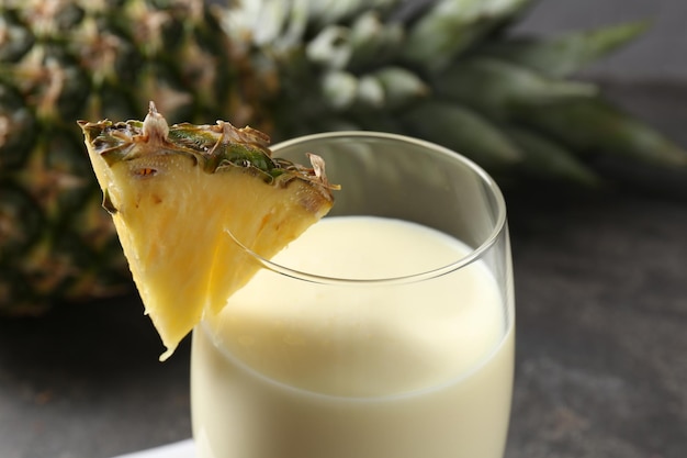 tasty pineapple smoothie in glass and fresh fruit on table closeup