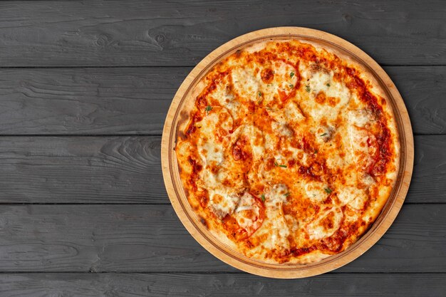 Вкусная пицца на черной деревянной поверхности, вид сверху