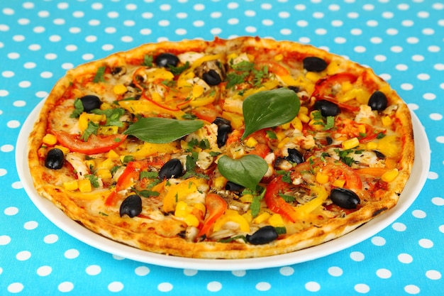 Tasty pizza on blue tablecloth closeup