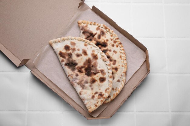 Tasty pizza calzones on white tiled table top view