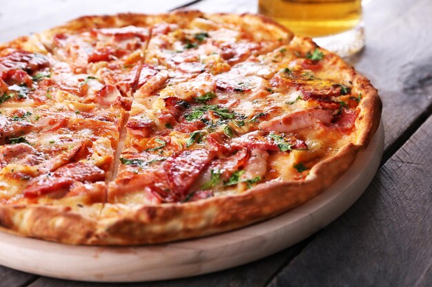 Tasty pizza and glass of beer are on wooden table close up