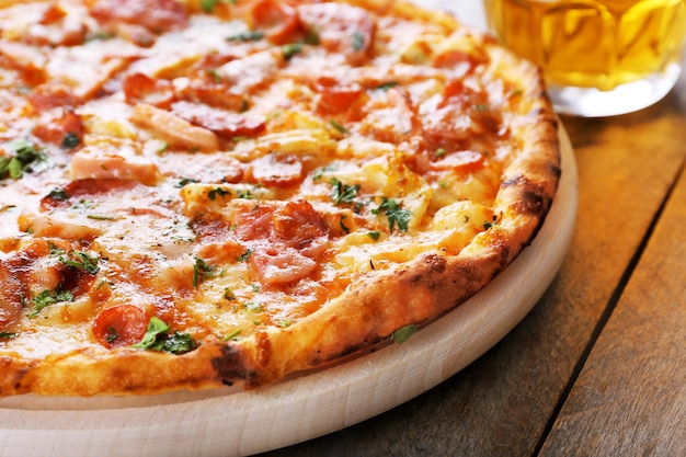 Tasty pizza and glass of beer are on wooden table close up