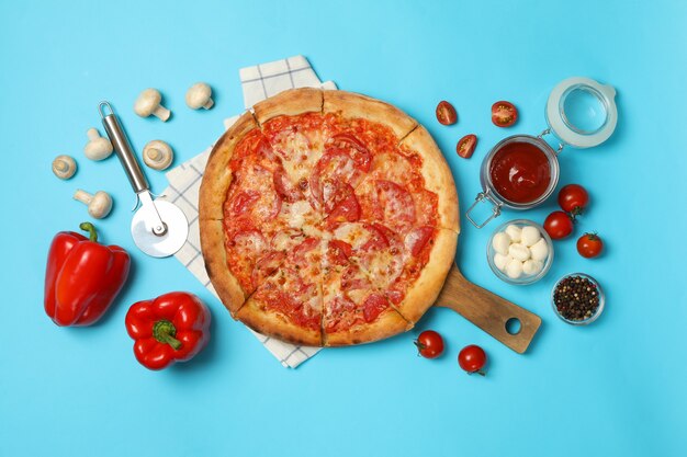 Tasty pizza and ingredients on blue