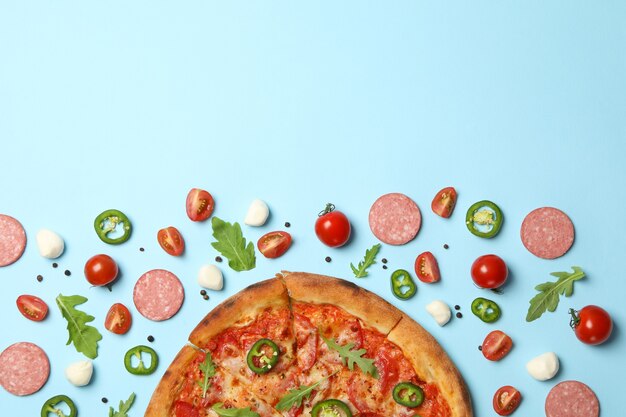 Tasty pizza and ingredients on blue