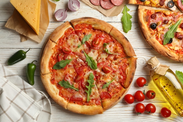 Tasty pizza and ingredients on wooden table