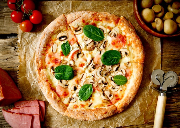 Tasty pizza and ingridients. On a wooden background