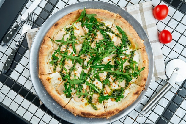 Tasty pizza with chicken, arugula and parmesan on a white table. Italian traditional cuisine. Delicious food flat lay. Top view