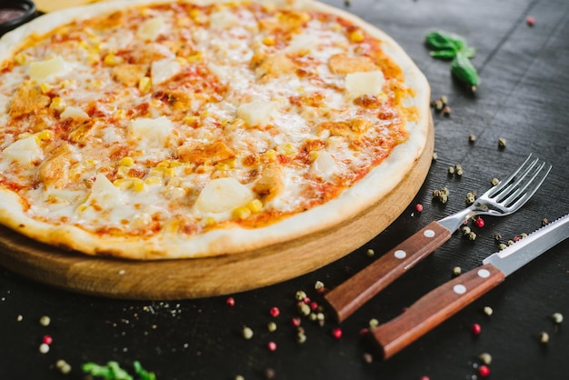 검은 배경에 햄, 옥수수, 치즈를 넣은 맛있는 피자