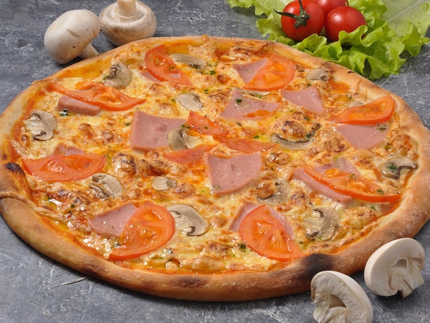 Tasty pizza with ham and mushrooms on a gray background