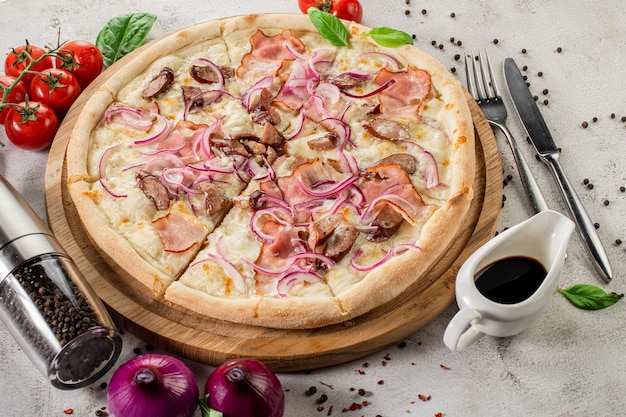 Tasty pizza with ham mushrooms and onion on the concrete background