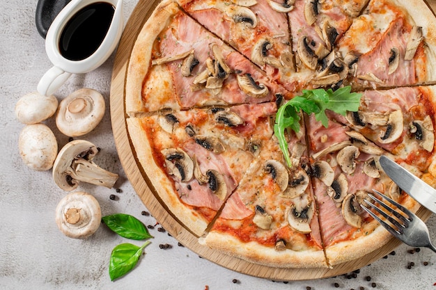 Tasty pizza with ham mushrooms and onion on the concrete background