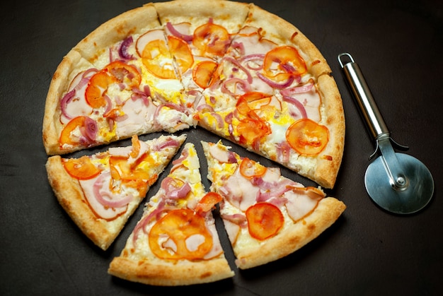 tasty pizza with ham, tomato, chili pepper, tomato sauce, mozzarella cheese on a stone background