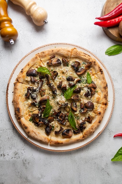 写真 灰色の背景のチーズとバジルで提供されたキノコで美味しいピザ