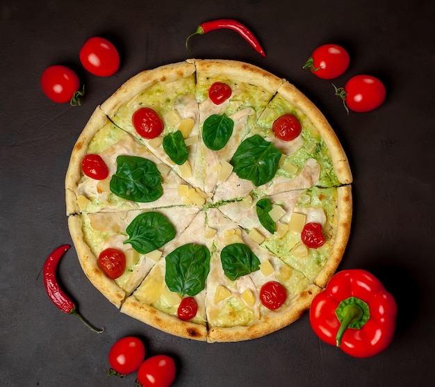 Gustosa pizza con ananas, pomodori, mozzarella, filetto di pollo su uno sfondo di pietra