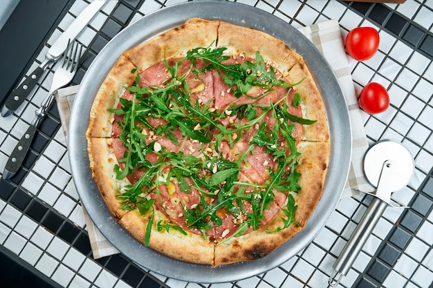 Tasty pizza with salami, arugula and parmesan on a white table. Italian traditional cuisine. Delicious food flat lay. Top view