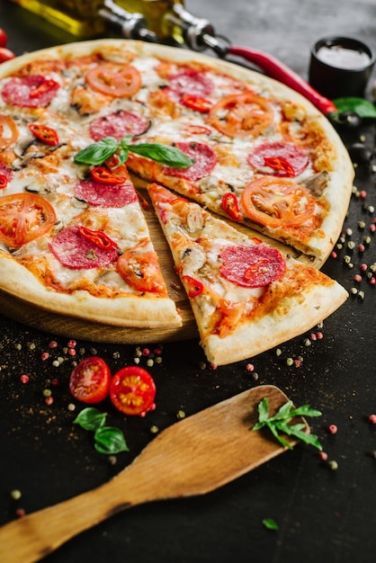 Tasty pizza with salami and cheese on black background