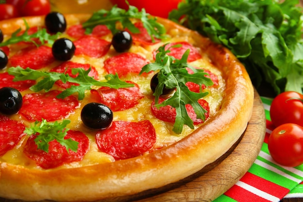 Tasty pizza with salami on decorated wooden table close up