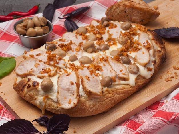 Tasty pizza with turkey and mushrooms on a wooden board