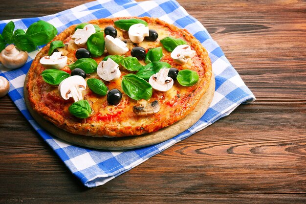 Tasty pizza with vegetables and basil on table close up