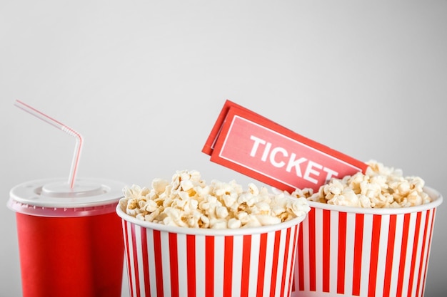 Tasty popcorn drink and tickets on light background