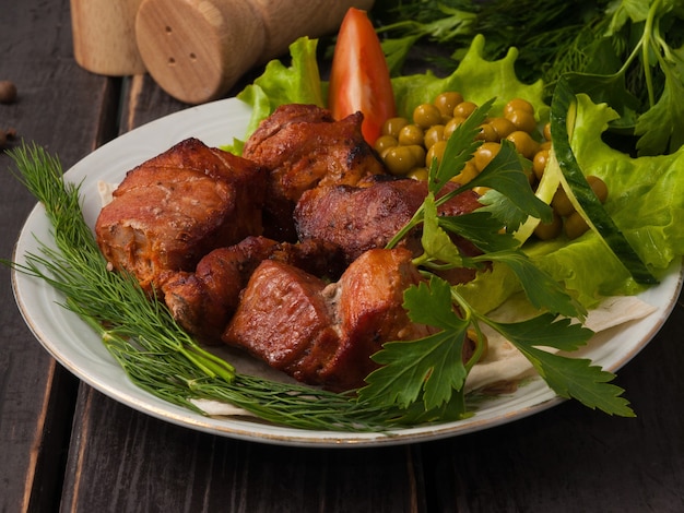 채소로 장식 된 접시에 맛있는 돼지 고기 케밥