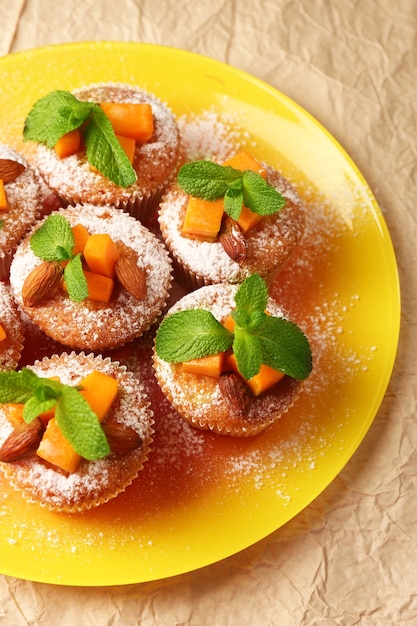 Tasty pumpkin muffins on brown paper