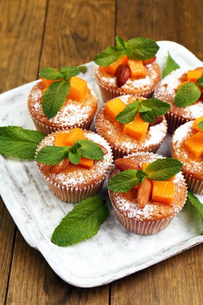 Tasty pumpkin muffins on wooden table