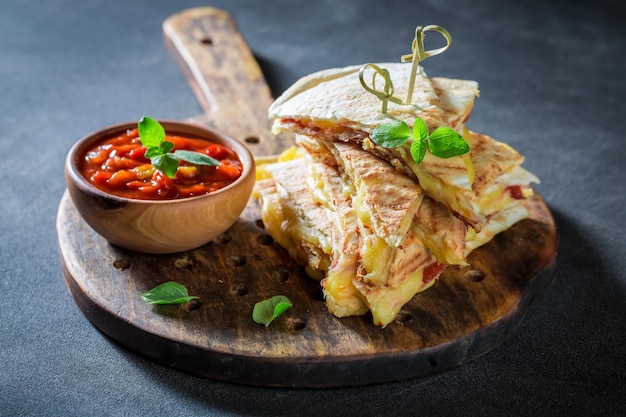 Tasty quesadilla made of tortilla with sauce and herbs