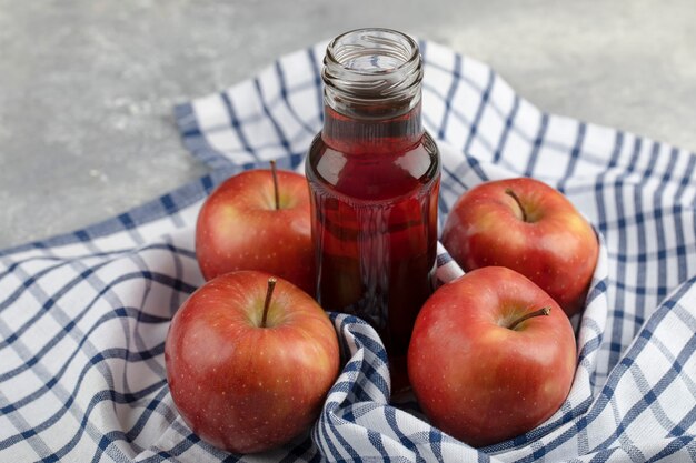 Tasty red apples and glass of red juice on striped tablecloth. 