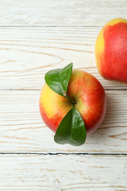 Tasty red apples on white wooden table