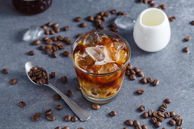 Tasty refreshing iced coffee with ice cubes in glasses on bright background. Closeup