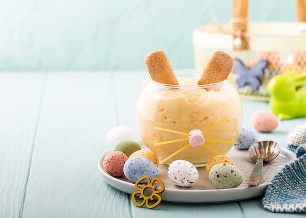 Tasty rice pudding dessert decorated of Easter Bunny with colourful quail eggs. Holiday helthy food concept with copy space