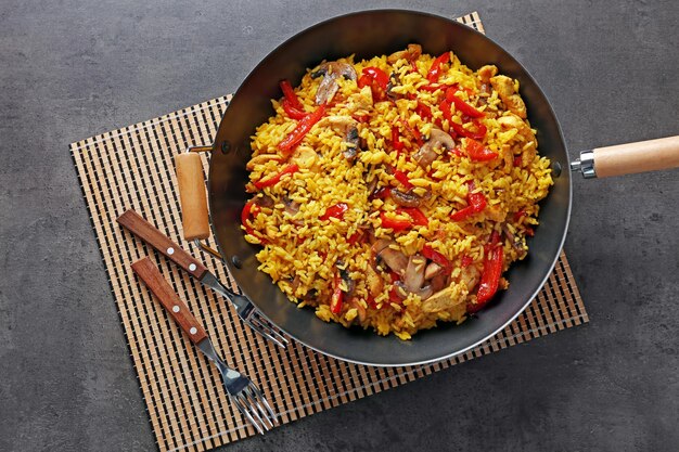 Tasty rice with vegetables in frying pan on grey table