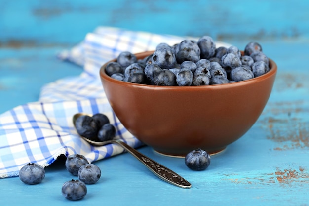 Tasty ripe blueberries in bowl on wooden table