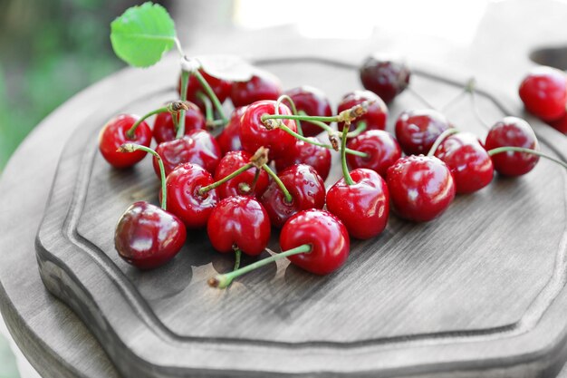 Tasty ripe cherries on wooden board outdoors