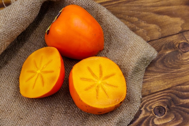 Tasty ripe persimmon fruits on a wooden table