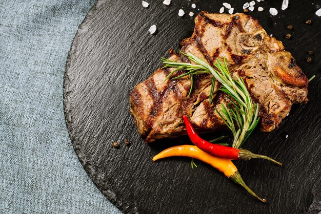 Tasty roasted steak with spices on the wooden background