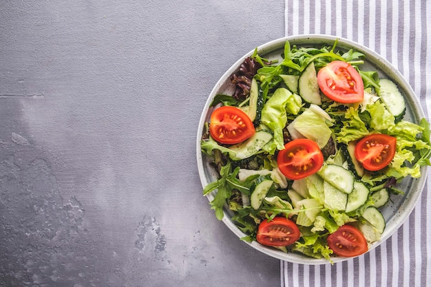 Tasty salad with mix of fresh greens cucumbers and tomatoes Diet food concept Top view with copy space