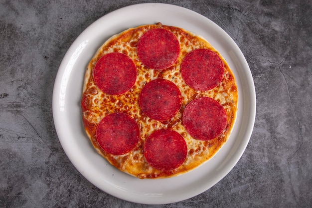 Gustosa pizza al salame e ingredienti per cucinare il pomodoro su fondo di cemento nero vista dall'alto della pizza al salame caldolay flat