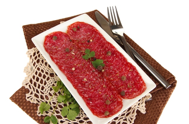 Tasty salami on plate on napkin isolated on white