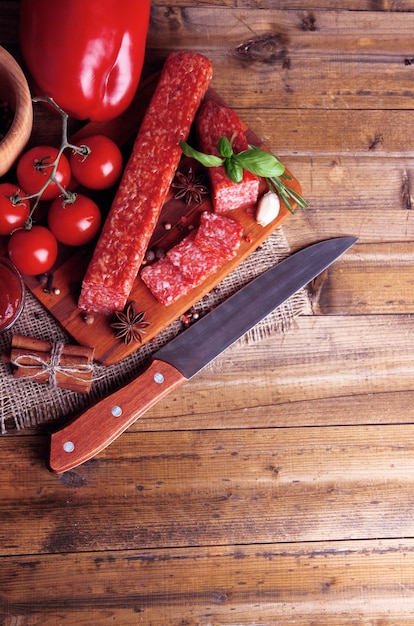 Tasty salami sausage and spices on wooden background