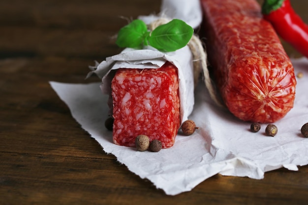 Tasty salami sausage and spices on wooden background